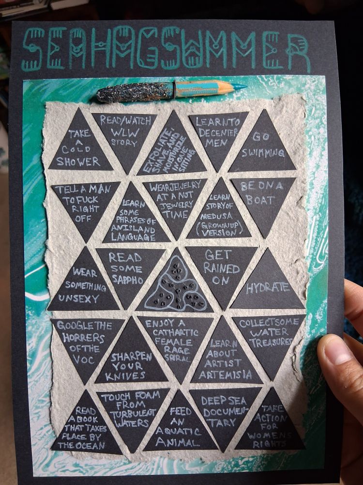 A homemade bingo card that has "Sea Hag Summer" written at the top in teal. The bingo squares are actually black triangles with white writing. They are glued to a greyish blue background. This has a marbleized teal border, and a black border around that. There is a short teal pencil attached at the top, which is encrusted with gold and turquoise. The squares are all follows: Take a cold shower, read/watch a WLW story, exfoliate shave and moisturize in one sitting, learn to decenter men, go swimming, tell a man to fuck right off, learn some phrases of an island language, wear jewelry at a now jewelry time, learn grown up story of Medusa, be on a boat, wear something unsexy, read some Sappho, a middle triangle with an abstract pattern of lines and punched holes, get rained on, hydrate, google the horrors of the VOC, sharpen your knives, enjoy a cathartic female rage spiral, learn about artist Artemisia, collect some water treasures, read a book that takes place by the ocean, touch foam from turbulent waters, feed an aquatic animal, deep sea documentary, and take action for women's rights.