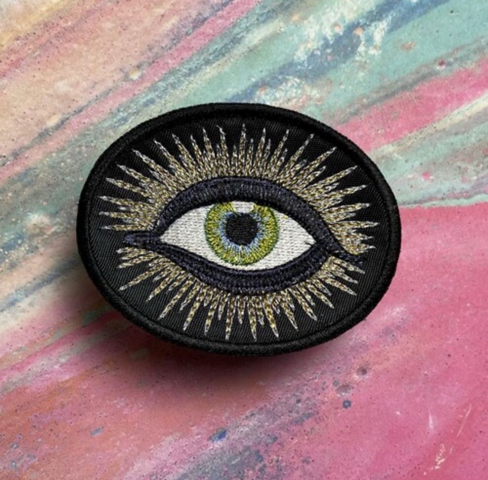 A patch, with an embroidered all seeing eye with green/hazel coloring 
