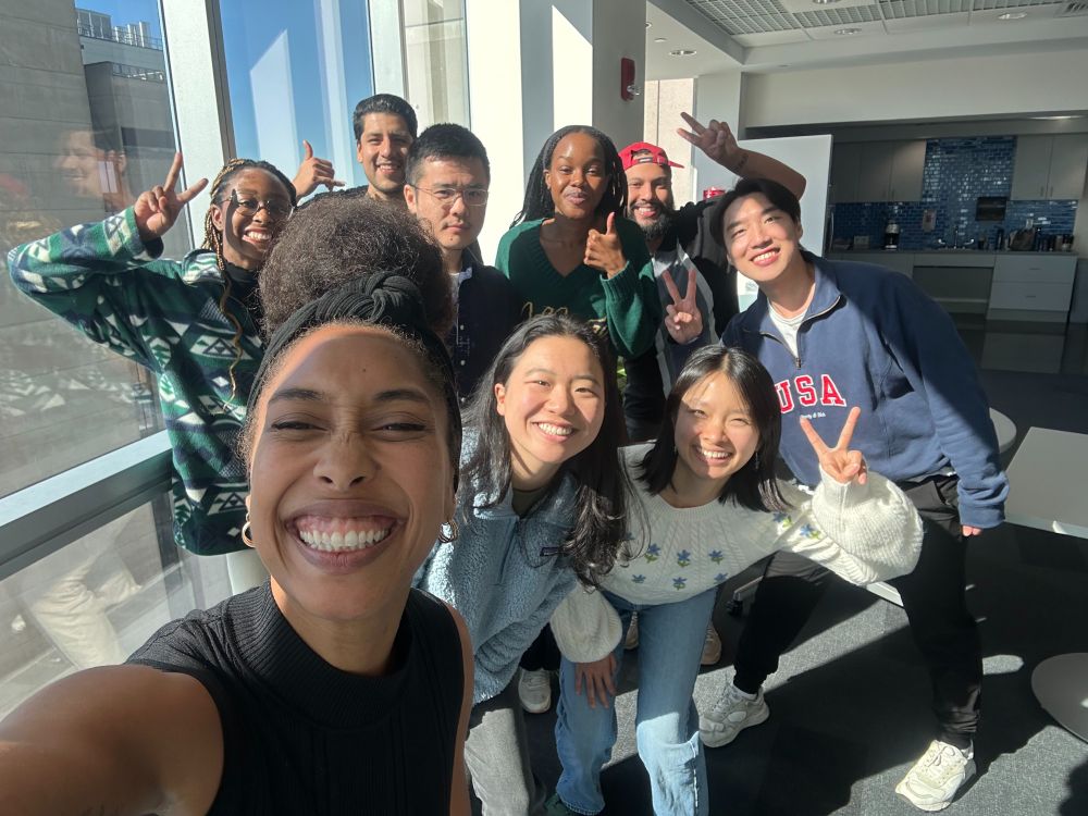 Brielle is pictured in a selfie with her lab standing behind her smiling. Some are holding up peace signs or thumbs up and the sun is shining on them brightly. 
