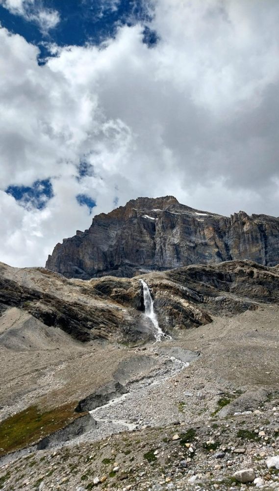 The photo shows a mountain in Aosta Valley with a rocky wall, all around stones and rocks from which a waterfall descends. The name Granta Parey comes from the dialect and means 