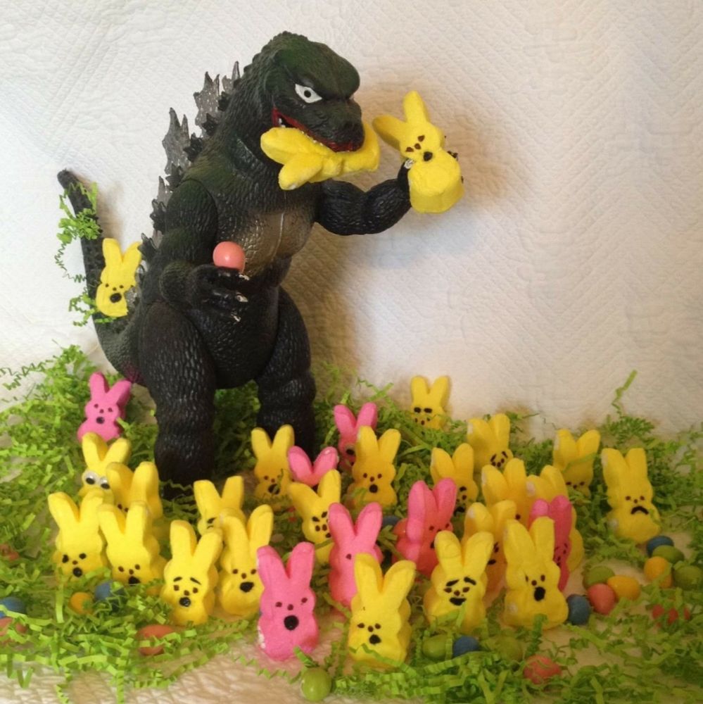 Godzilla rampaging through a crowd of pink and yellow Peeps, with one in his hand and one in his mouth