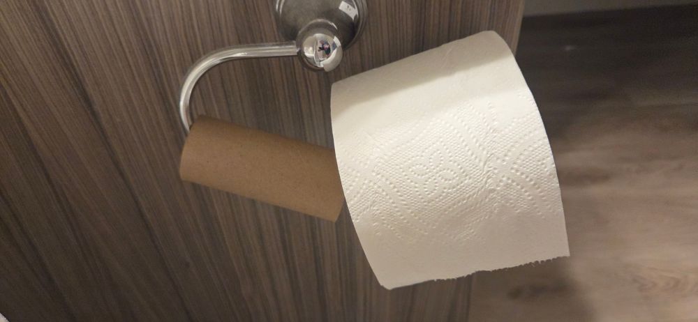 Picture of an empty toilet paper roll on the slide on tp roll holder (THE EASIEST ONE) is pushed back for new roll to go on. Basically pointless because 