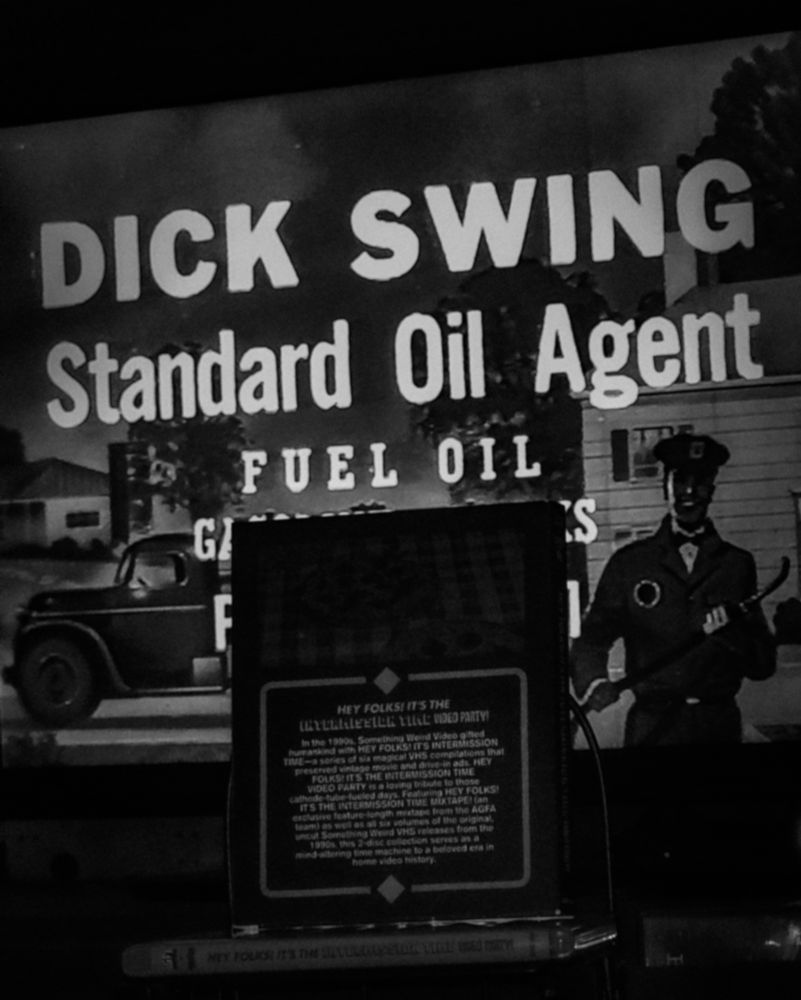 A slipcover on top of a blu-ray case also for a release of volumes of compilations called "Hey Folks! It's The Intermission Time Video Party". Behind is something from Volume 4 playing on a television, the words "DICK SWING Standard Oil Agent FUEL OIL" fully visible on the screen. But with other text obscured by the slipcover.
