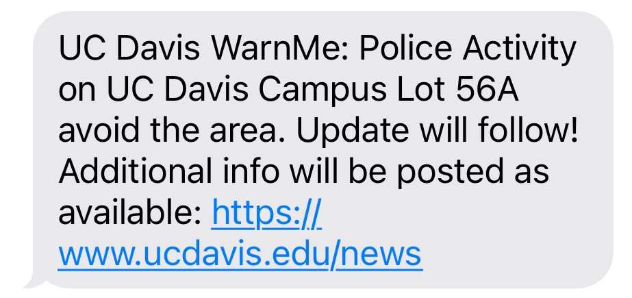 A text message reading “UC Davis WarnMe: Police Activity on UC Davis Campus Lot 56A avoid the area. Update will follow! Additional info will be posted as available: https://www.ucdavis.edu/news” with a gray bubble background. 