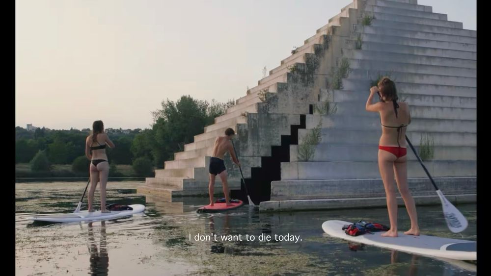 A group of paddleboarders. The subtitle reads “I don’t want to die today”. 