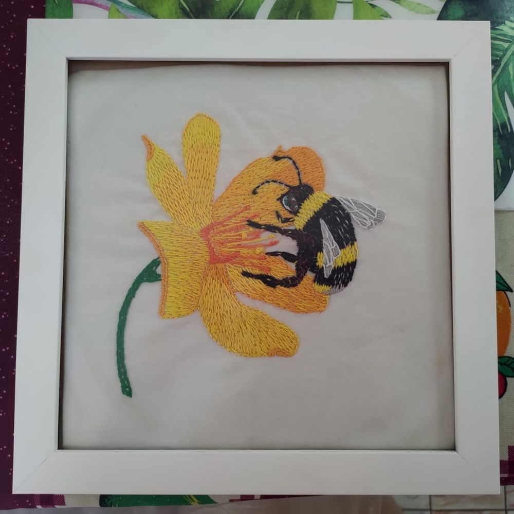 Bordado enquadrado de uma Abelha chegando no pólen de uma flor amarela