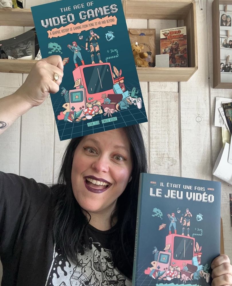 Image of Jen holding a real version of the comic book in French and posing with a fake version of the book in English. The cover is in Émilie Rouge’s signature teals and salmon pink.