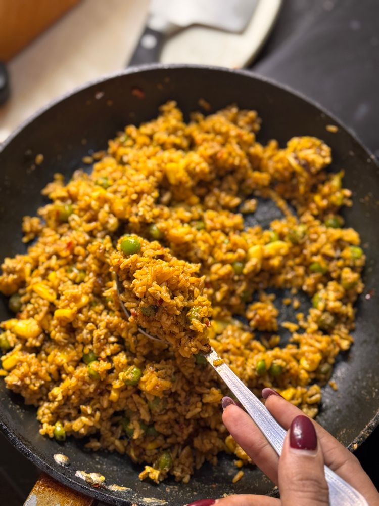 Skillet of sticky fried rice made with corn, peas and eggs in a spicy black bean sauce.