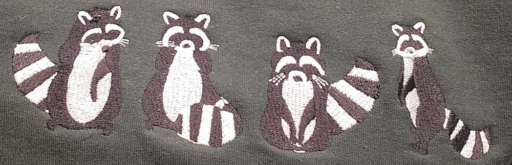 Four embroidered raccoons in various sitting and standing positions on