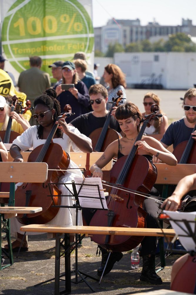 sehr viele Celli auf dem Tempelhofer Feld, im Mittelpunkt des Bildes zwei junge Frauen