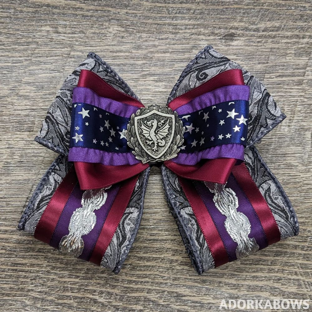 A purple, burgundy, blue, and silver bow. Pin in the center by Doctor Gus.
