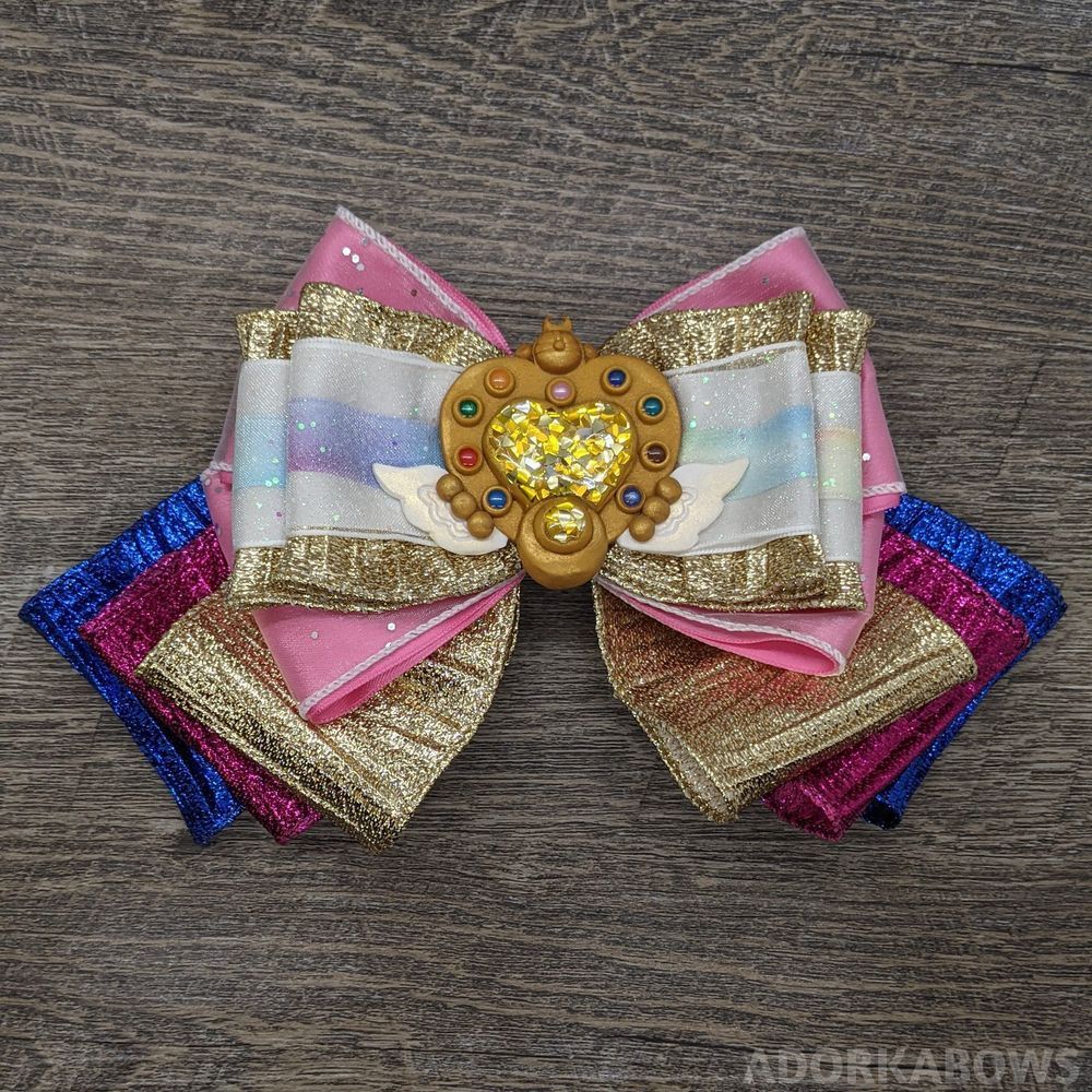 Pink, blue, and gold bow with a Sailor Moon brooch in the center.

