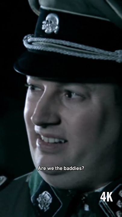 Mitchell saying to Webb "Hans, are we the baddies?" in a Nazi uniform with a Totenkopf like the one on Graham Platner's chest on his hat band. 