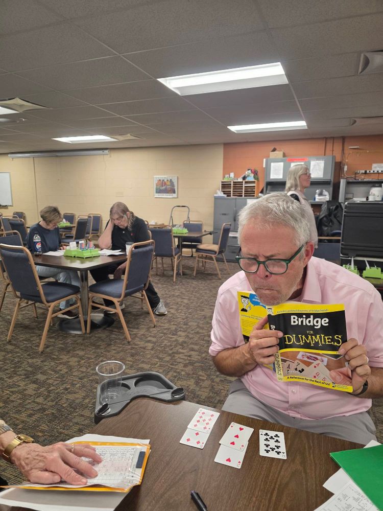 BGJ at the Bridge club, sitting dummy and reading "Brudge for Dummies" 