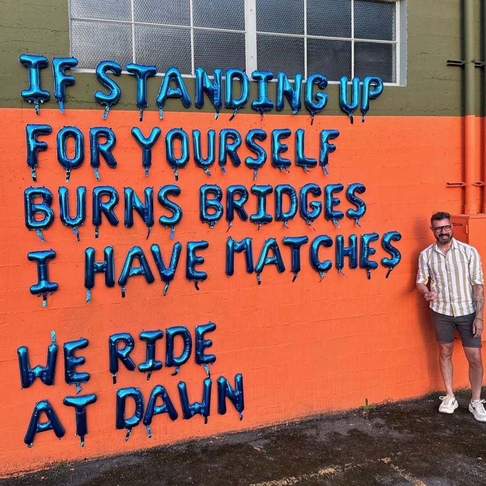 An orange wall showing blue inflatable balloons spelling out a quote. Street art by Blcksmth on Instagram.

"If standing up for yourself burns bridges, I have matches. We ride at dawn"