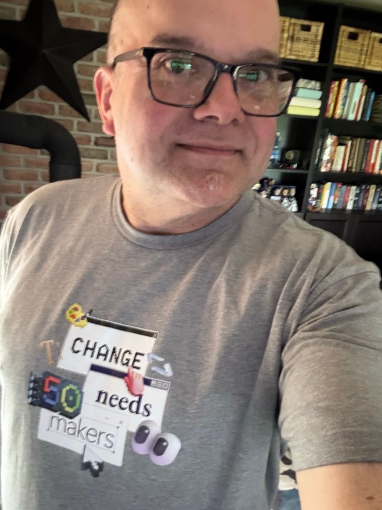A picture of Alvin Ashcraft, wearing glasses and a grey Microsoft "Change needs makers" 50th anniversary t-shirt.