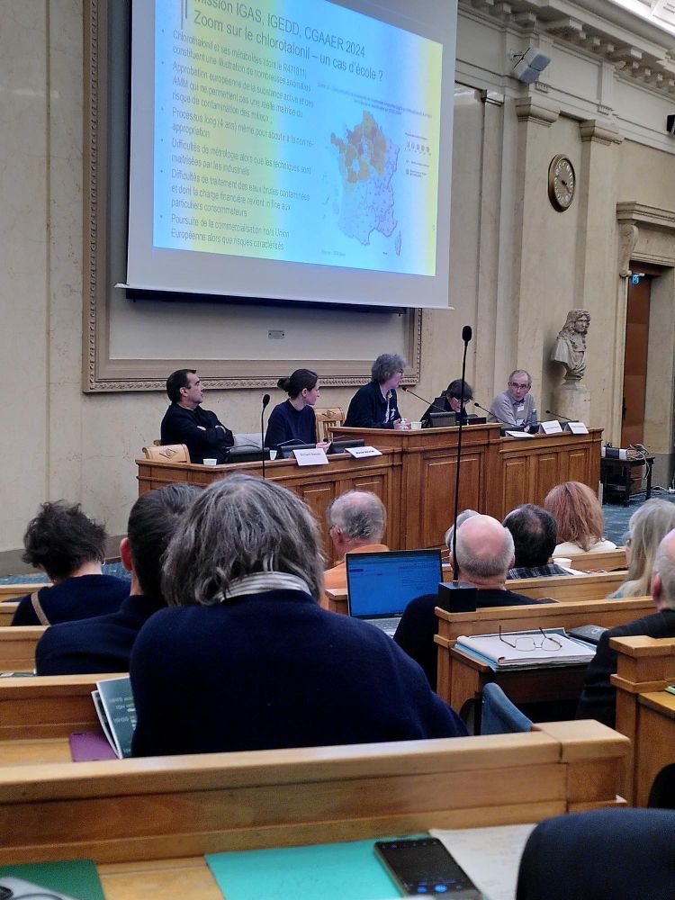 Colloque à l'Assemblée Nationale des bancs t une estrade en bois avec 5 personnes  