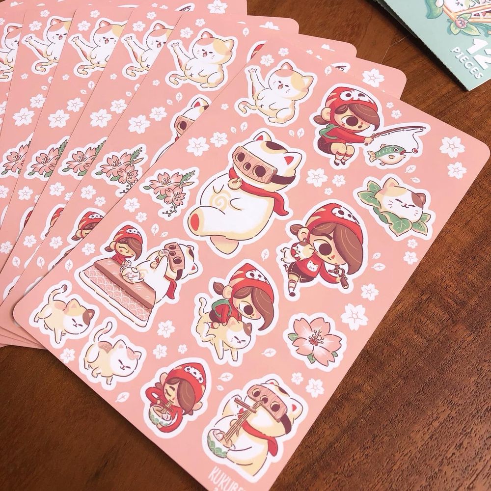 A sticker sheet with a pink background featuring characters from the video game Mineko’s Night Market. 
