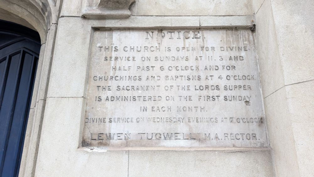 A church wall with a large stone reading: notice 
This church is open for divine service on Sundays at 11.30 and half past 6 o clock and for churching and baptisms at 4 o clock. The sacrament of the lord's supper is administered on the first Sunday of each month.

Divine service on Wednesday evenings at 7 o clock

Lewen tugwell, ma, rector 