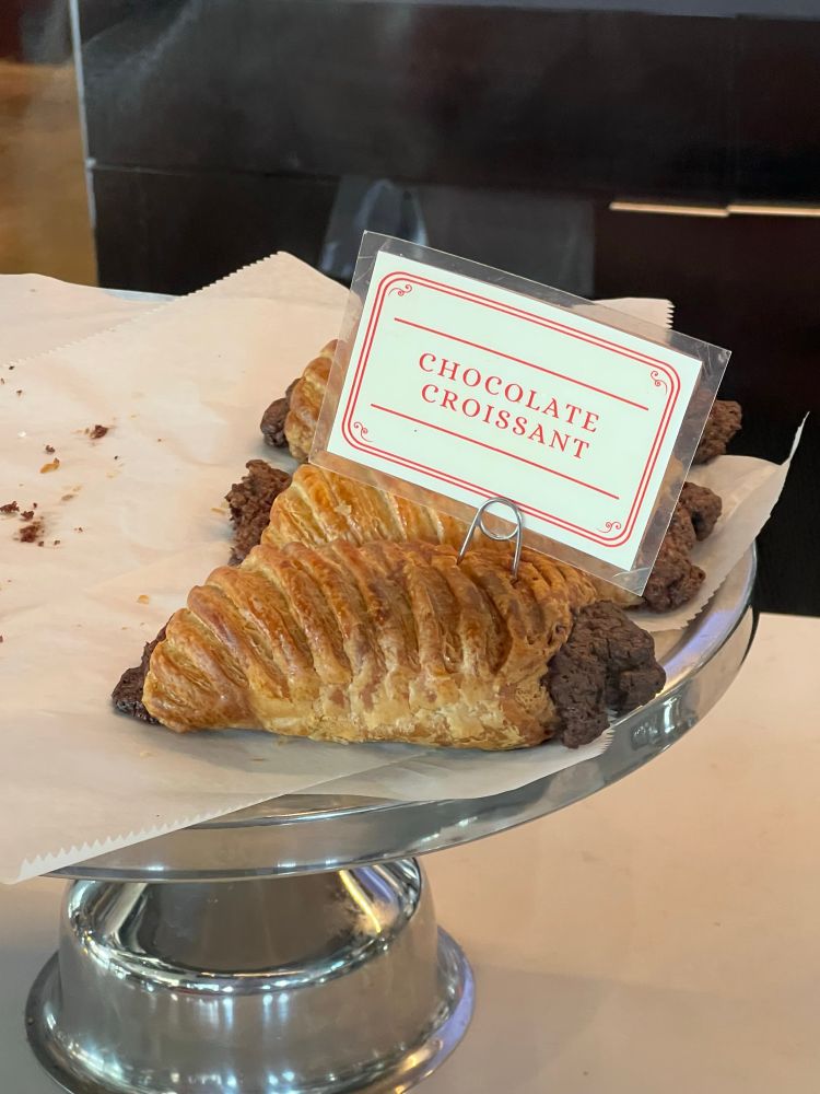 A “chocolate croissant” on a silver dish in a coffee shop that looks a lot more like “a cookie panini” 