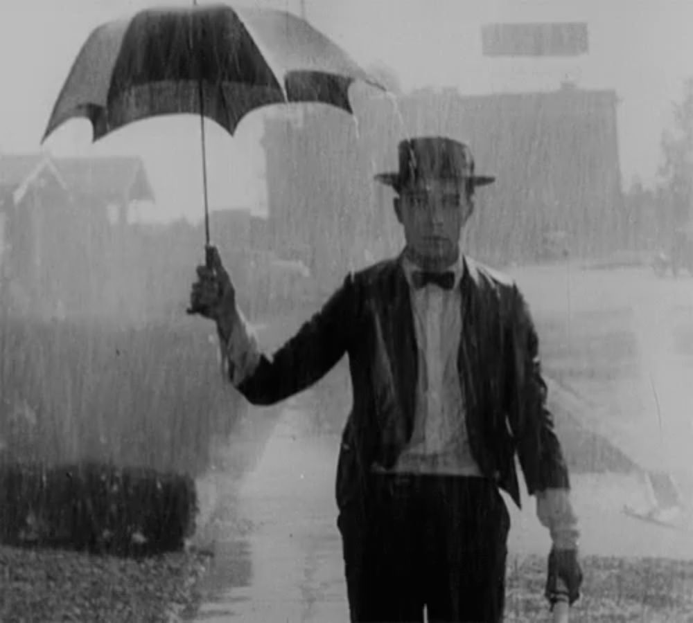 a man holding an umbrella in the rain with a billboard in the background