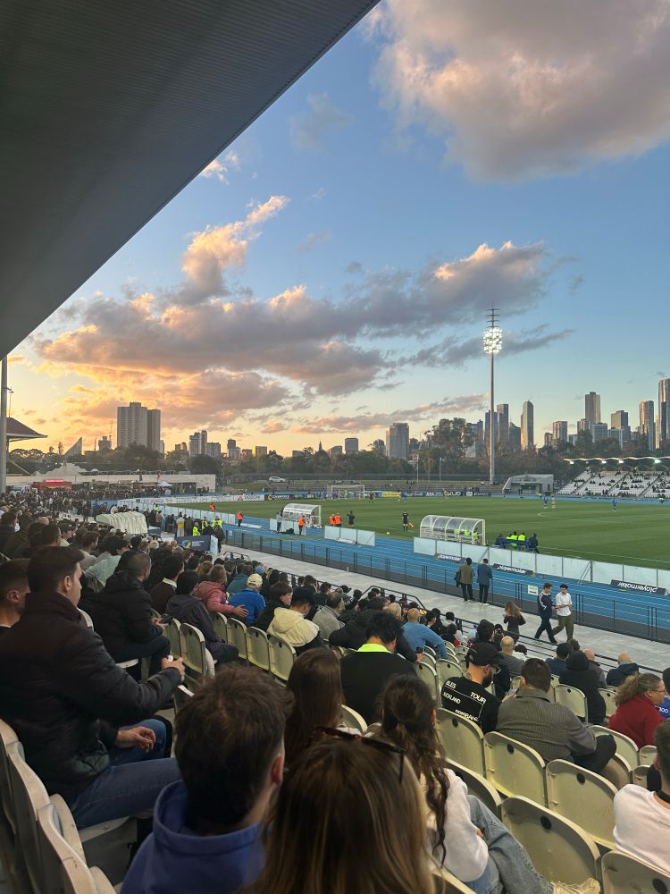 the crowd at South Melbourne v Sydney Olympic with a stunning sunset over Lakeside Stadium