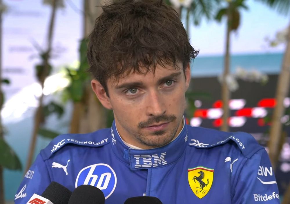 charles Leclerc in an interview after miami gp, with messy hair and wearing the ferrari blue race suit