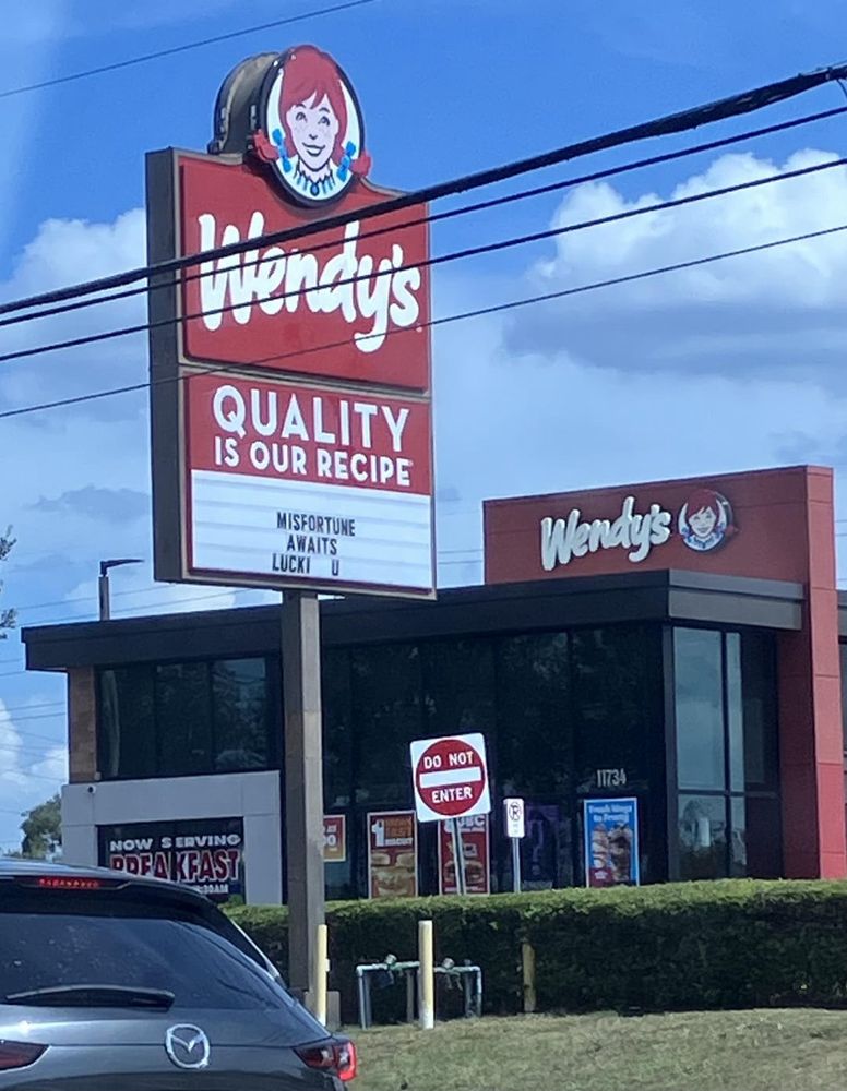 A photo of a Wendy’s. The marquee out front says, “MISFORTUNE AWAITS. LUCKI U.”
