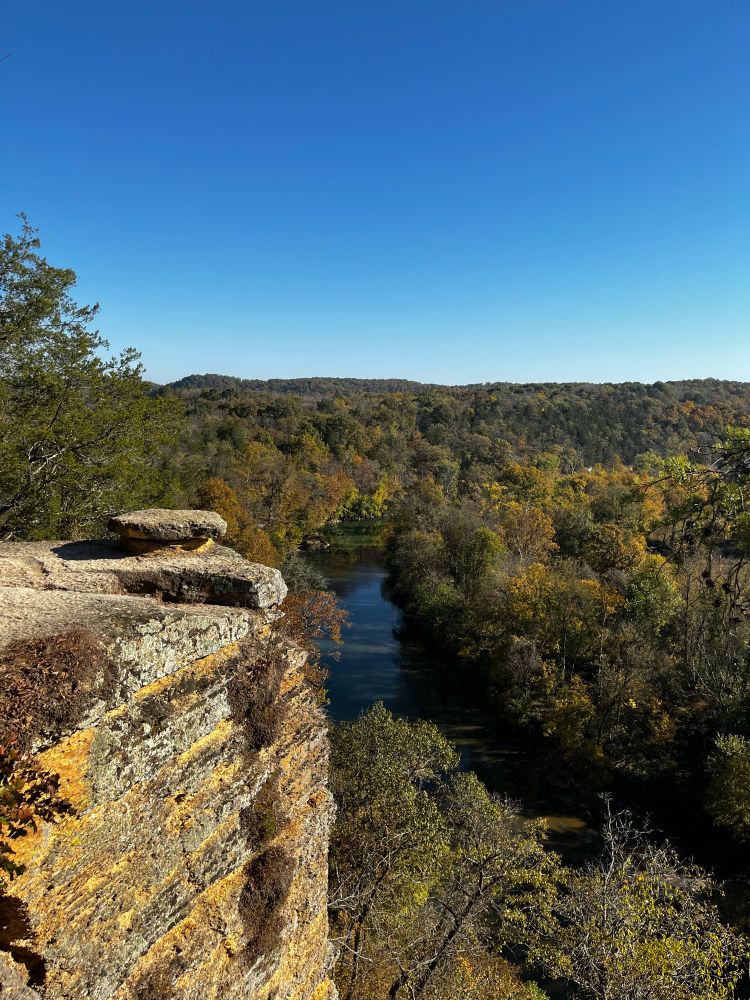 picture of a cliff on a ridgeline with a river and trees that are changing colors below