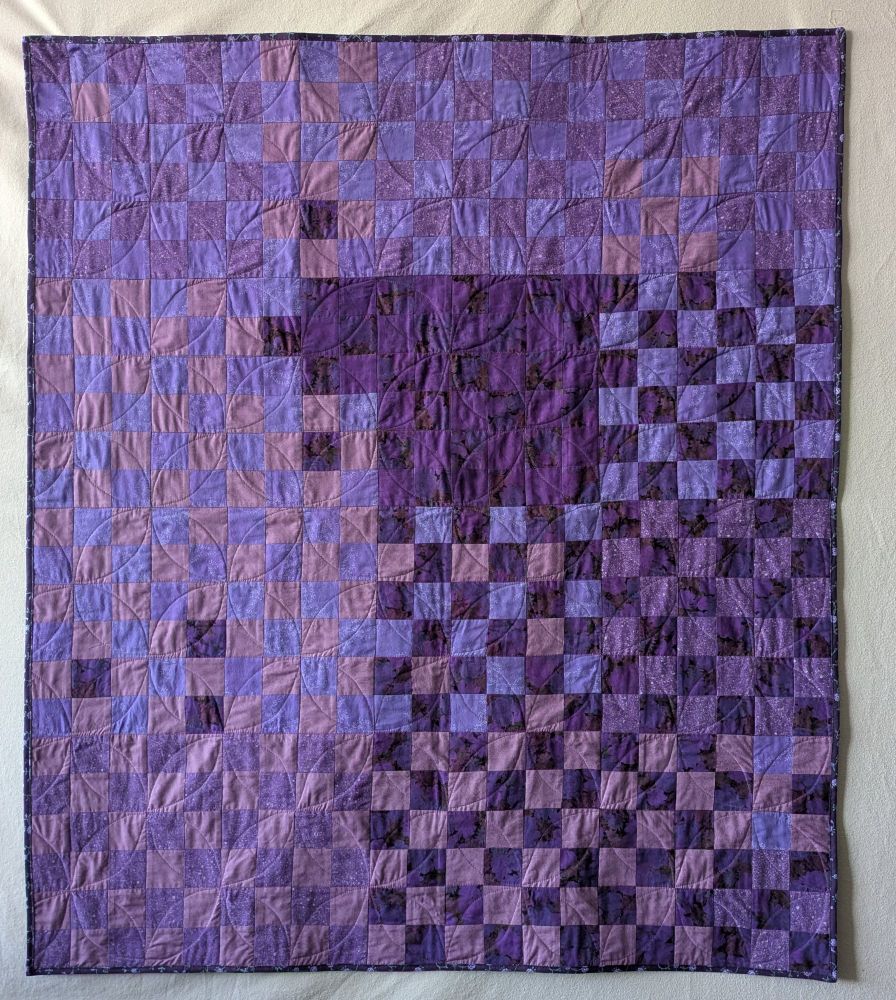 Nine-patch quilt overdyed with purple and quilted with allover orange peel pattern
