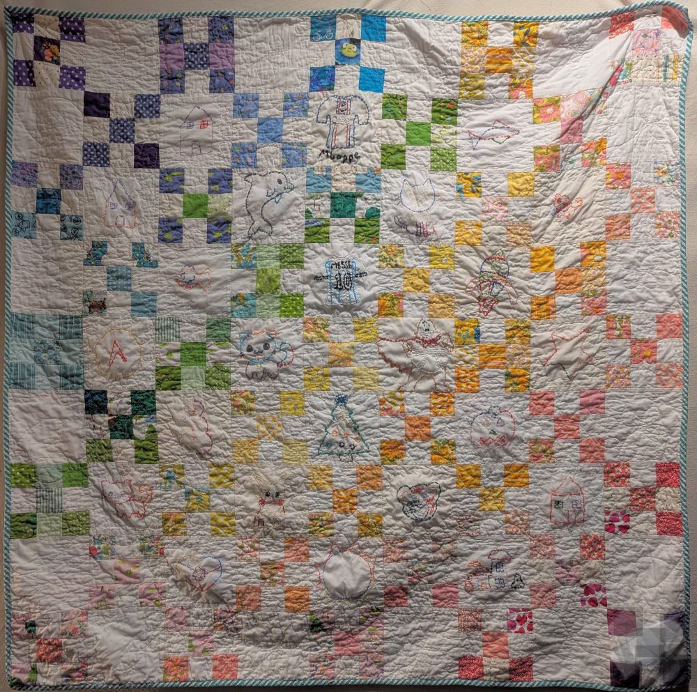 Cheerful rainbow nine patch quilt with alternating embroidered squares. 