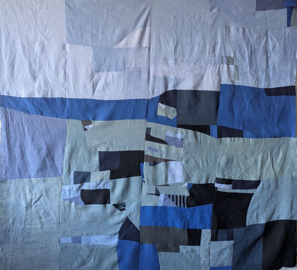 Quilt top made of scrap linen. Some of the pieces have been overdyed with blue dye. 