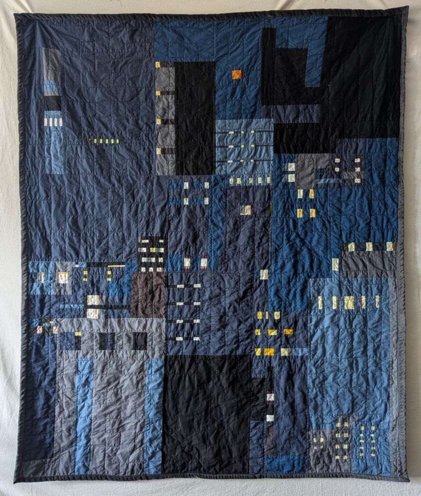 Scrap quilt depicting an urban skyline. Quilted with a Hilbert curve. 
