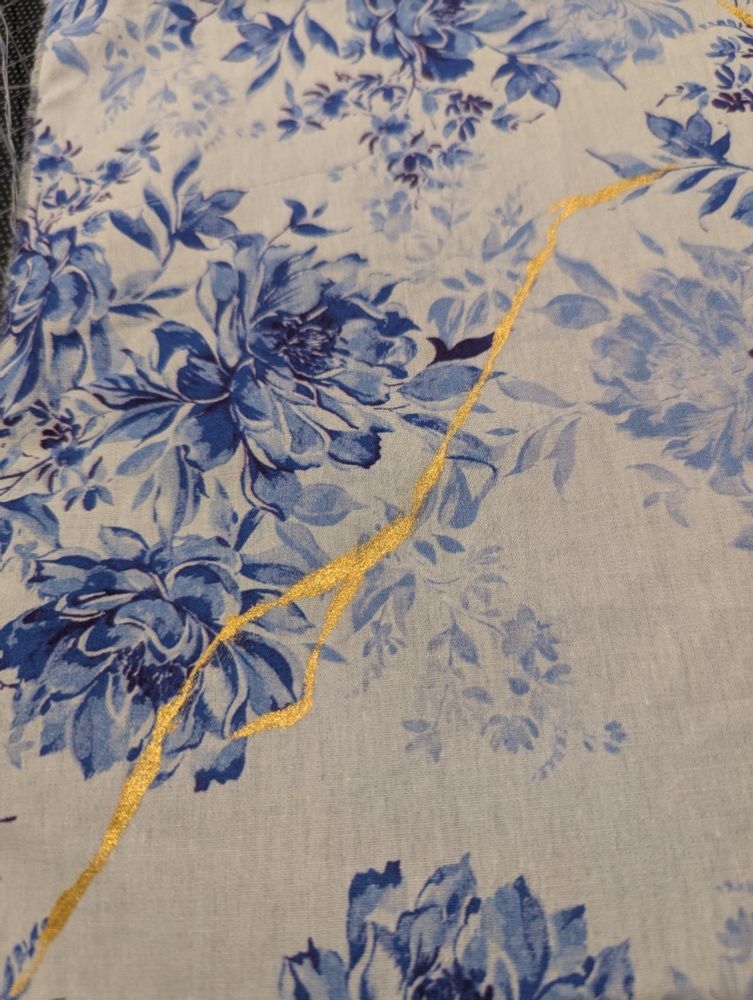 Blue floral fabric with gold lines painted onto it