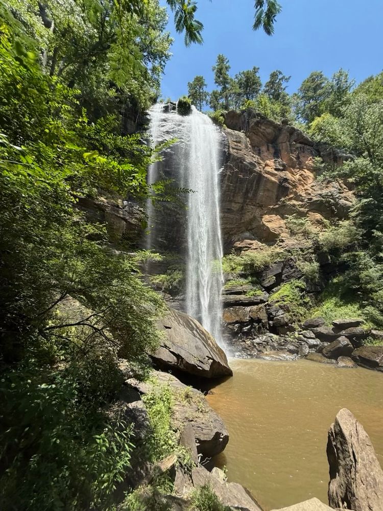 Tall waterfall and cliff face with waterfall centered and the bottom pool off to the right.  Toccoa Falls.