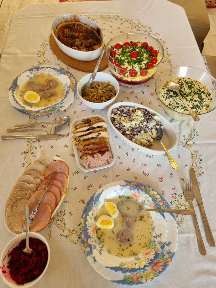 Ein Tisch voll gedeckt mit polnischen Speisen wie Żurek, Schichtsalat, Ćwikła, Kiełbasa. 