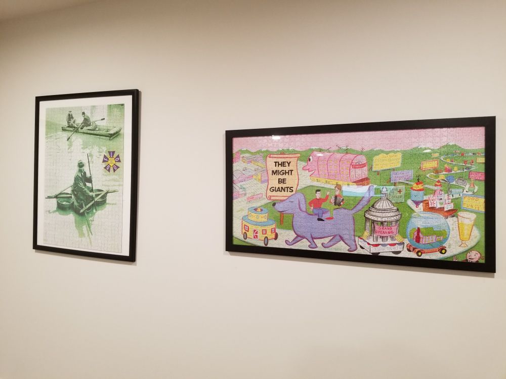 The image shows two framed puzzles of They Might Be Giants albums