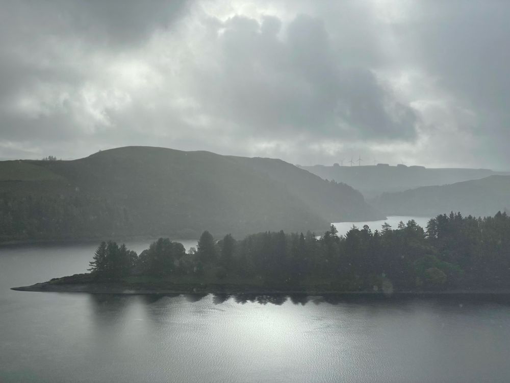 Y cronfa Llyn Clywedog yn y mynyddoedd uwchben y Drenewydd. The snaking reservoir Llyn Clywedog in the hills above Newtown, Powys. Brooding clouds fill the top of the frame.