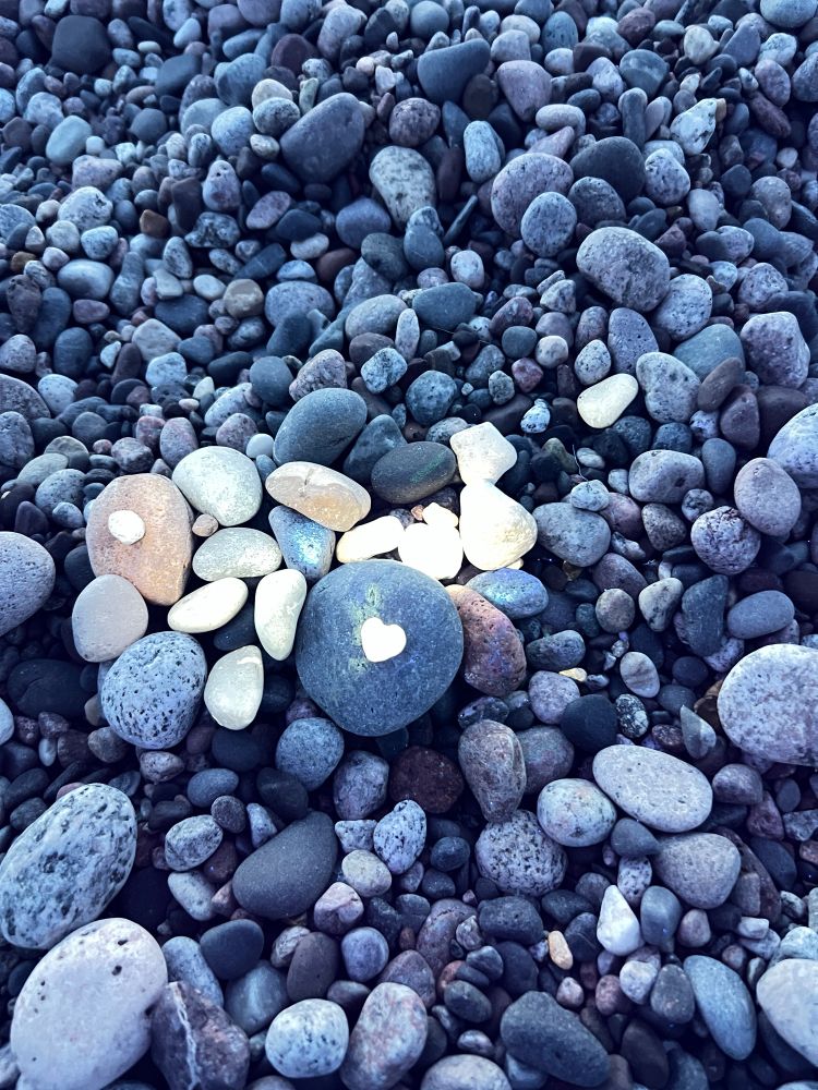 Water-worn stones, a cluster glowing under a uv flashlight, one heart-shaped stone on a darker round stone