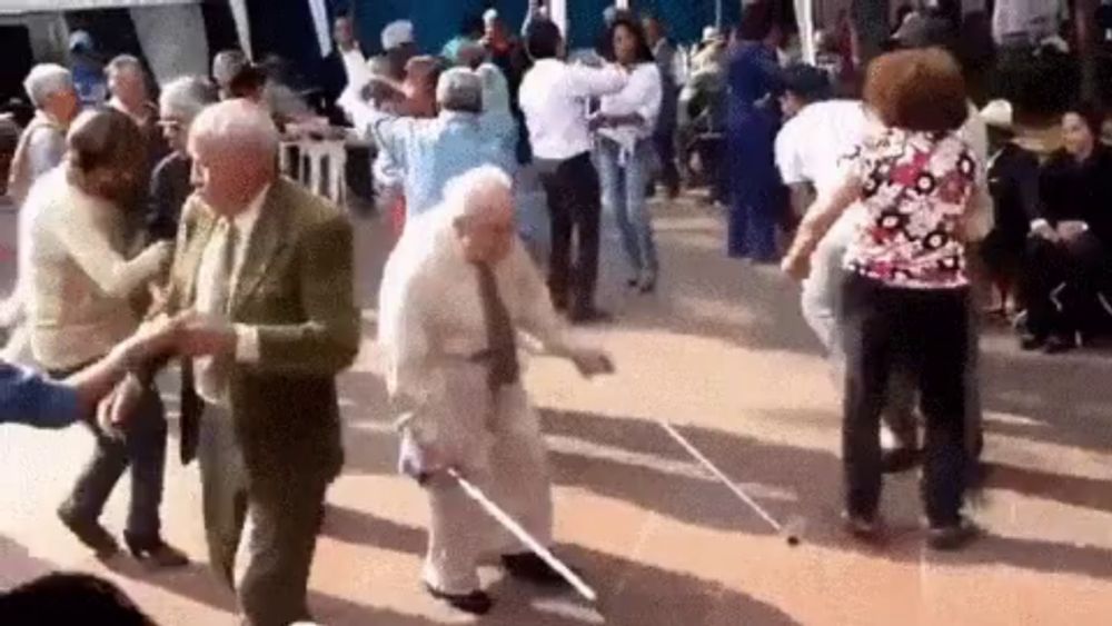 a group of elderly people are dancing together in a crowd .