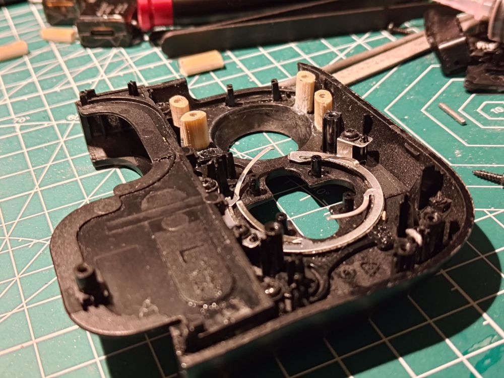 The inner side of a piece of a Razer Kishi controller, with four of the standoffs replaced by pieces of chopsticks. 