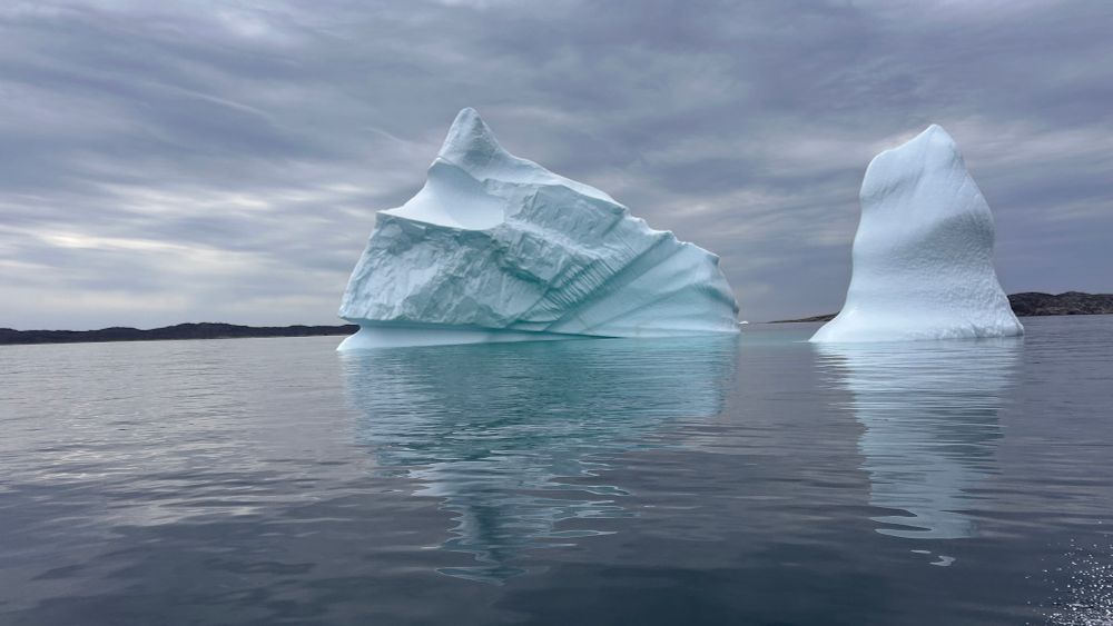 Two huge icebergs in a calm sea.