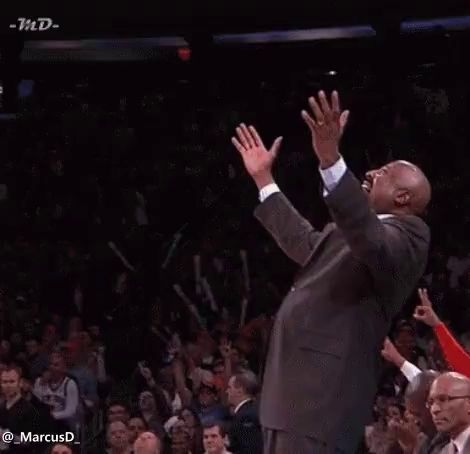 a man in a suit is standing in front of a crowd with his hands in the air