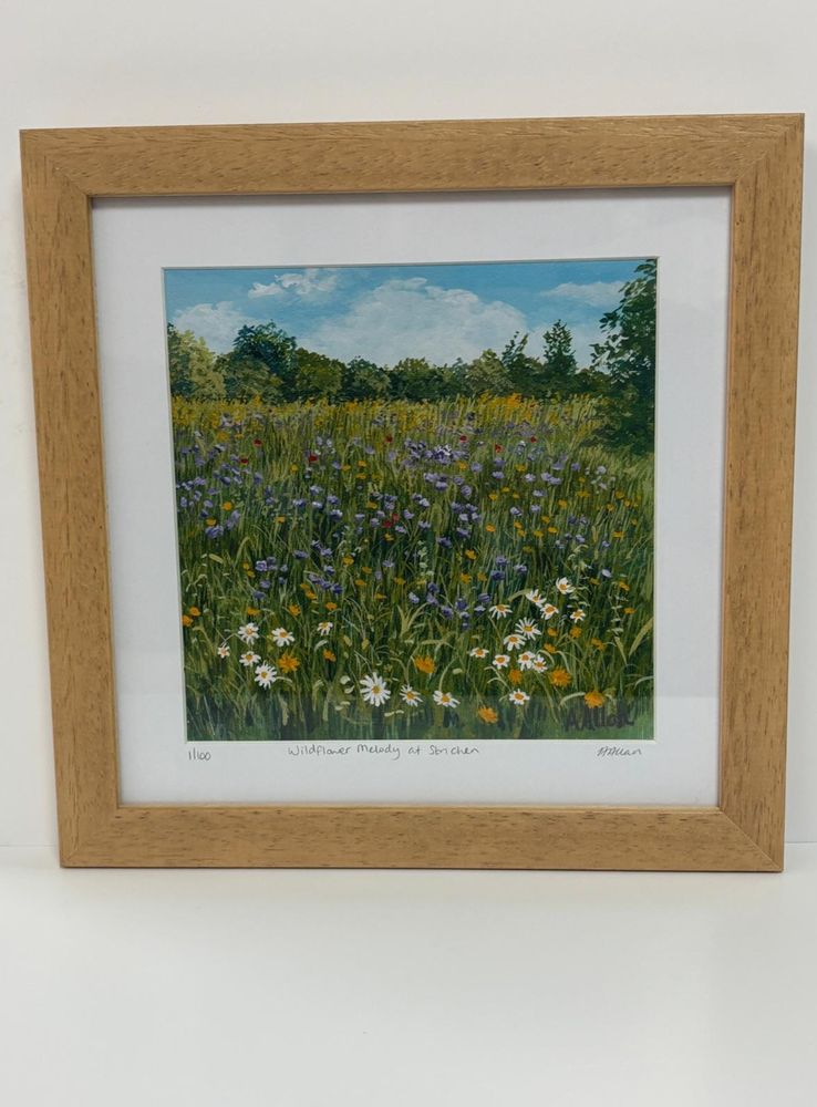 A print of an original artwork showing a wildflower meadow in a natural wood frame