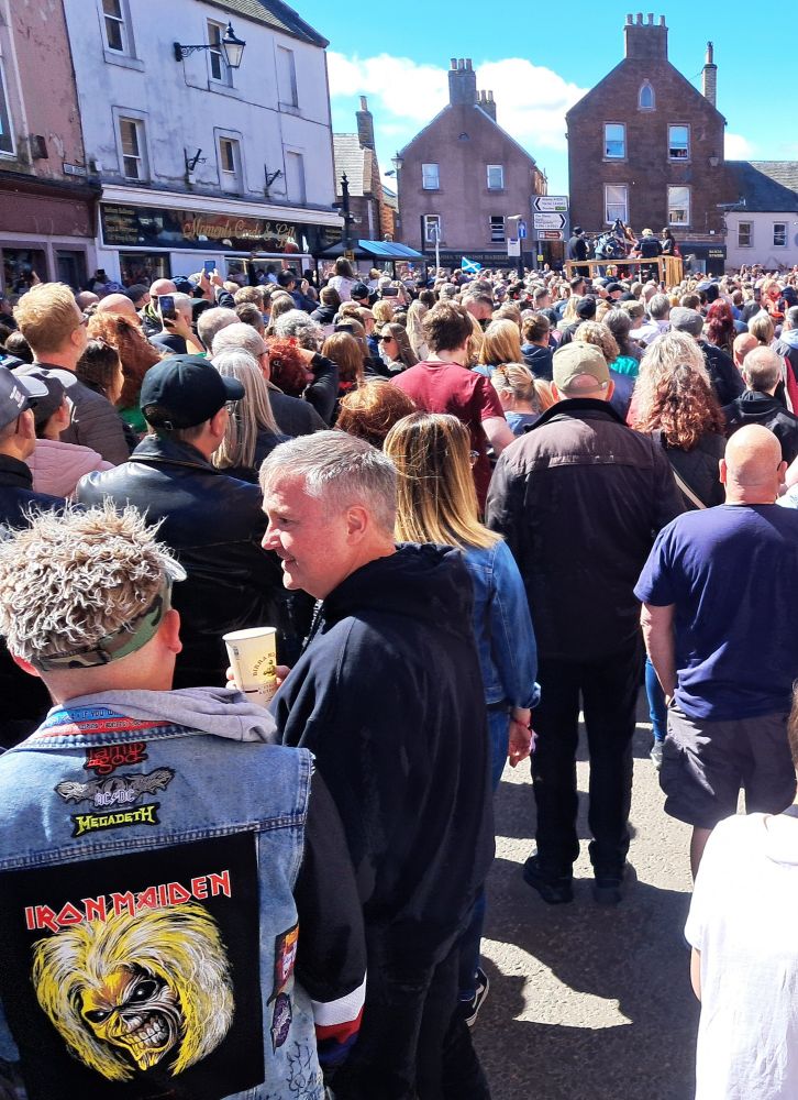 Kirriemuir town centre during Scotland's celebration of Ronald Belford 'Bon' Scott who lived there as a young child. A flat bed truck hosts a guest band playing It's a Long Way, along with a bagpiper