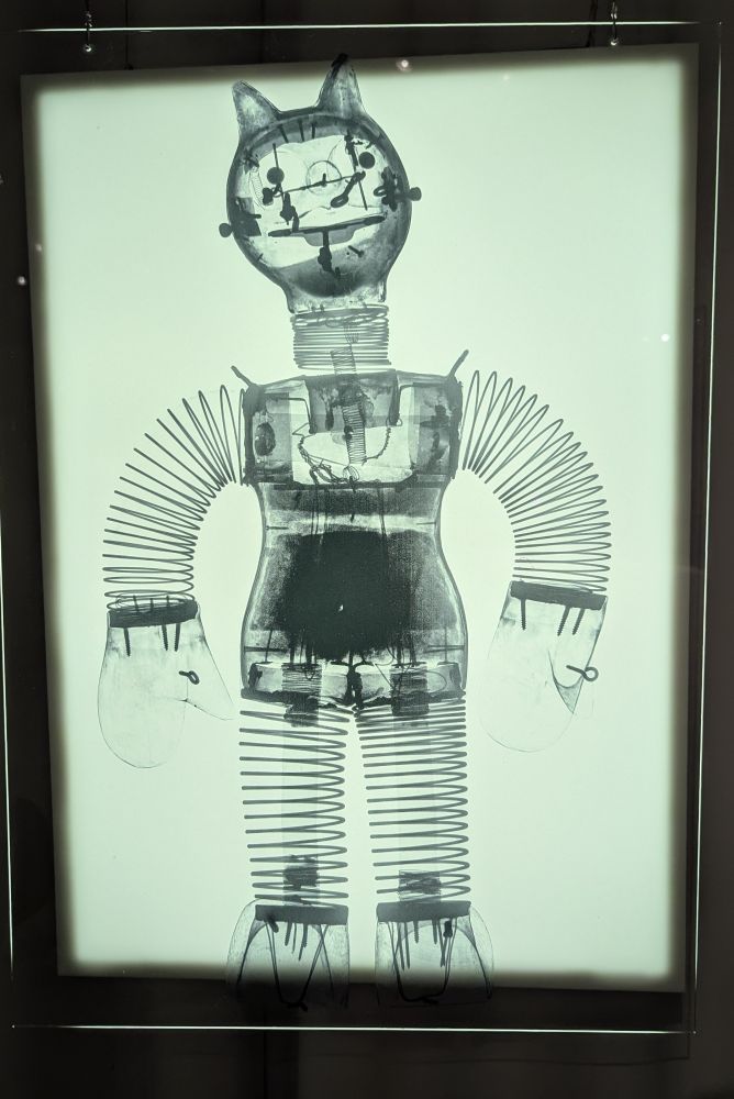 An x-ray photo of a string puppet depicting a humanoid with ears. Springs and nails are seen inside. 