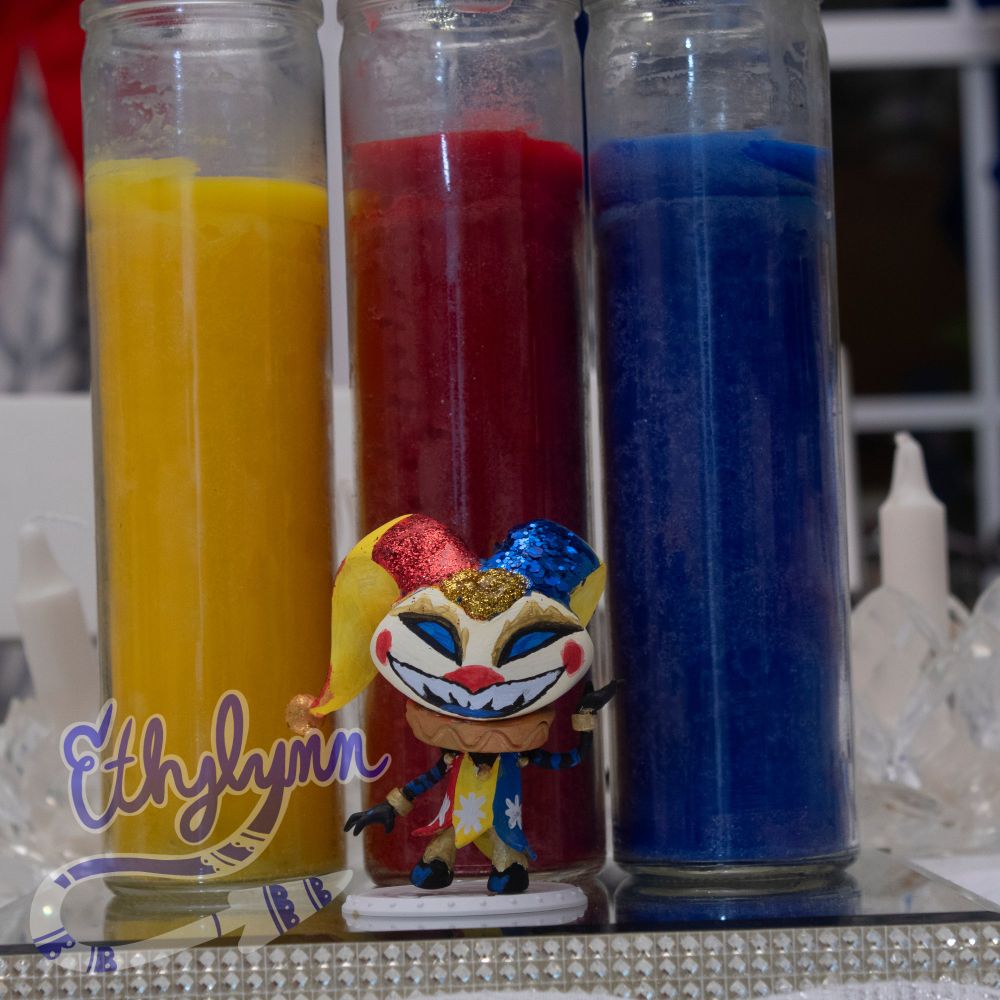 Front view of repainted Fizzie. Themed after HumanLight. Acrylic paint, metallic paint, and glitter glue. Standing in front of three yellow, red, and blue candles.