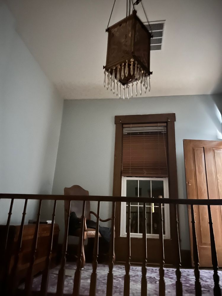 Stair landing with chair, hanging light and rails