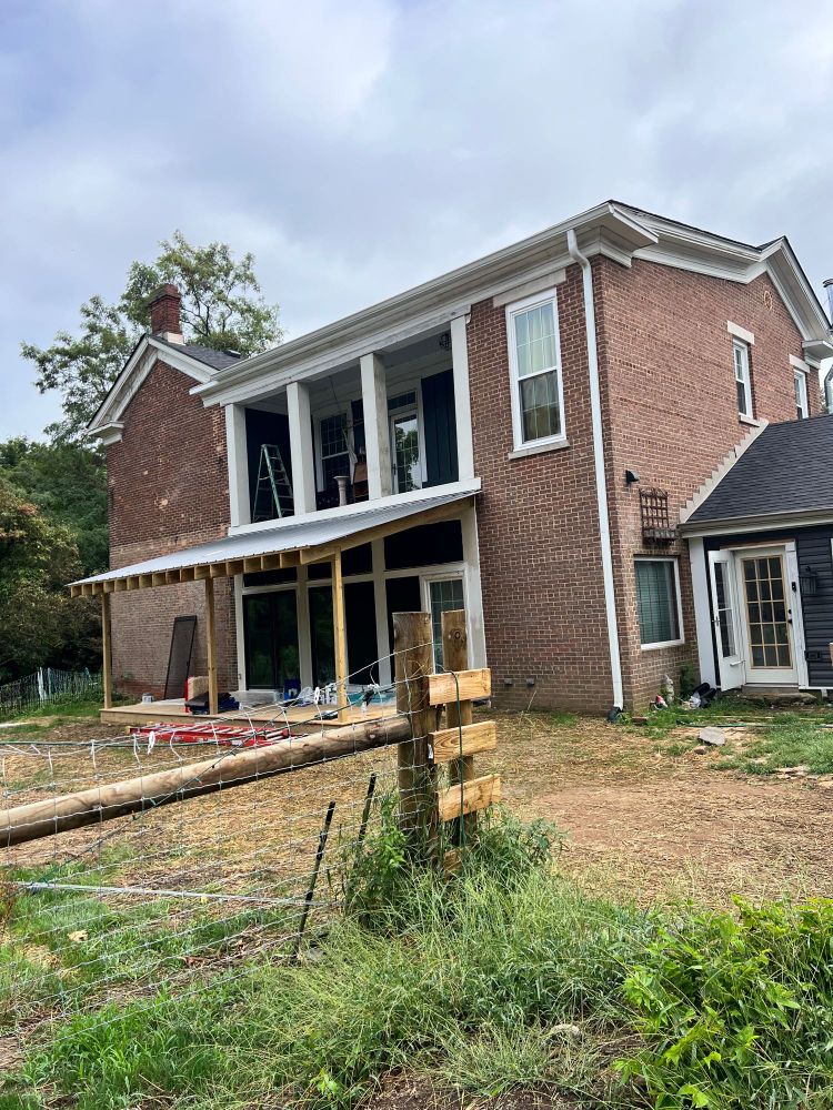 Two story brick house with balcony and construction debris