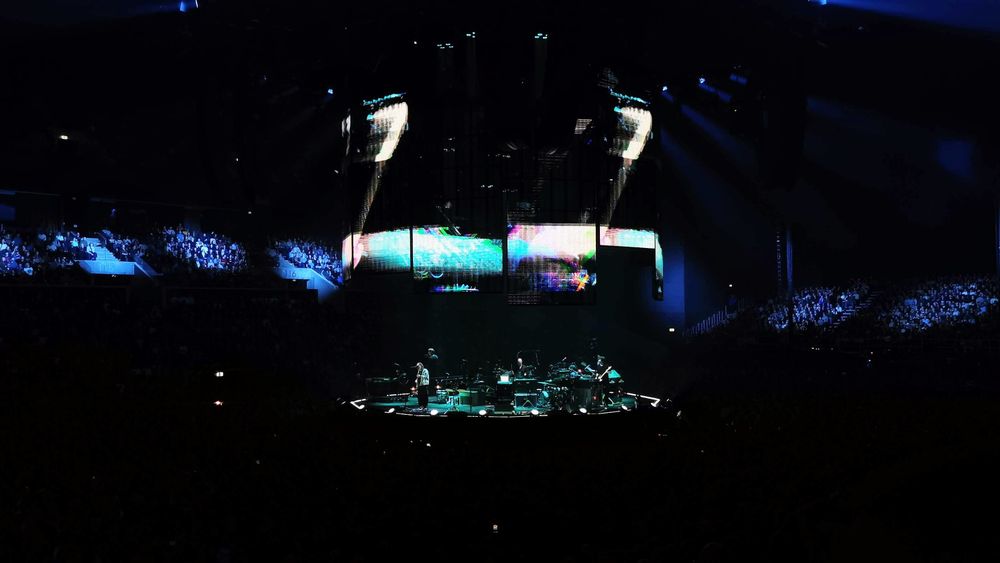 Photo de Radiohead sur scène, prise depuis le public. C'est un peu flou. très sombre, on ne voit pas grand-chose, mais c'est très joli quand-même.